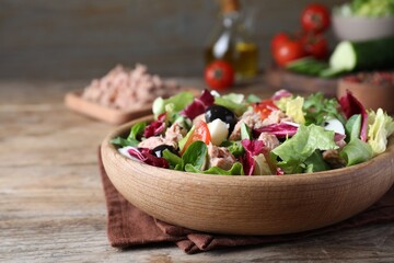 Bowl of delicious salad with canned tuna and vegetables on wooden table, space for text