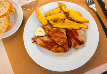 Juicy delicious fried pork with French fries on a plate