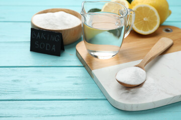 Baking soda, vinegar and cut lemons on light blue wooden table