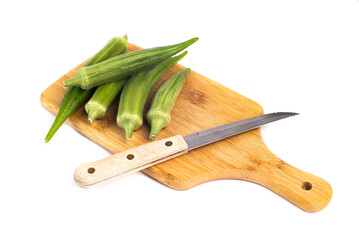 green okra pods on cutting board with a knife. Isolated on white.