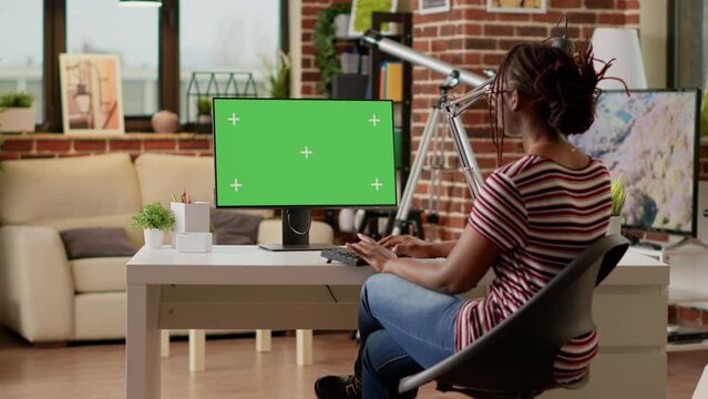 Company employee using greenscreen on computer and doing remote work, looking at monitor. Student woman working remotely with isolated chroma key template, blank mockup background.