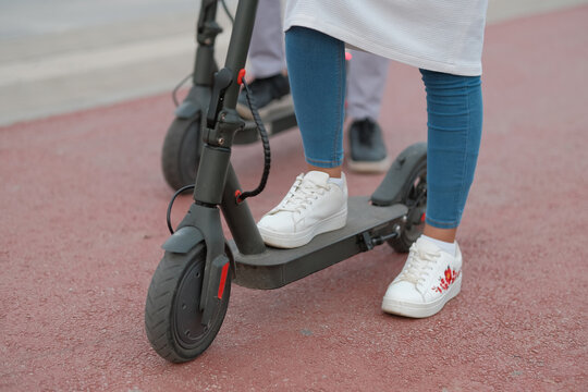 Two Friends Couple Having Fun Riding An Electric Scooter Through The City Street Track.