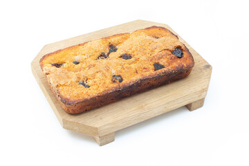 piece of craft cornbread home made Johnny bread made of corn flour and fig pieces on a wooden cutting board isolated on a white background