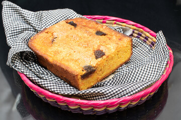 piece of craft cornbread home made Johnny bread made of corn flour and fig pieces on a little basket with a gray piece of fabric
