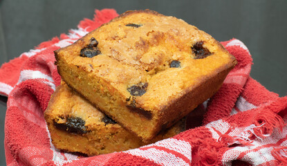 piece of craft cornbread home made Johnny bread made of corn flour and fig pieces on a little basket with a red piece of fabric
