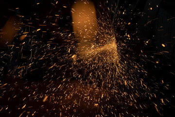 Sparks from grinder. Metal cutting. Bright lights in dark. Industrial background.