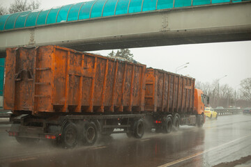 Truck with orange body. Big trailer. Transportation of waste.