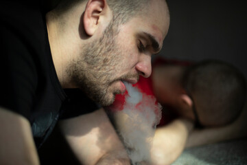 Fototapeta premium Guy smokes. Man with cigarette. Man is tired. Head in sunlight.