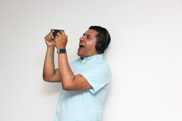 Latino adult man uses technology with his cell phone and headphones to listen to music, play video games, make video calls, watch series, and date on the app
