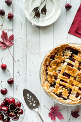 Top down view of a fall themed cherry pie with copy space to the left.