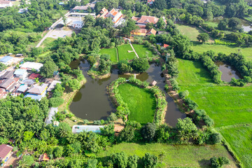 Obraz premium Drone view of Sufficiency Economy, Land full of agricultural activities with green rice fields, big ponds, and trees. Small houses and temple close by a pond.