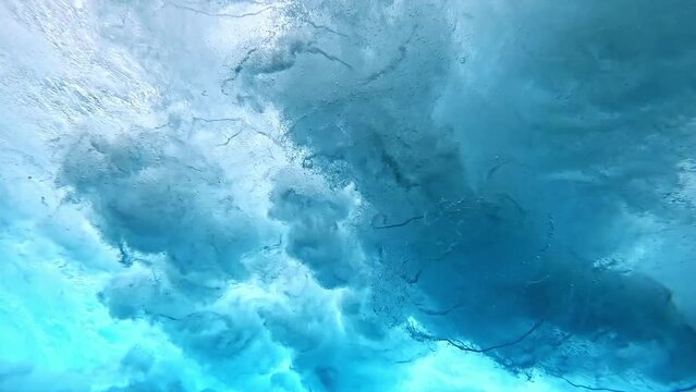 Underwater view of tube wave breaking over coral reef with spinning vortex, clouds. powerful nature, strong wave, danger of drowning. slow motion.