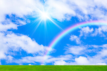 Obraz na płótnie Canvas 草原と青空に虹と太陽