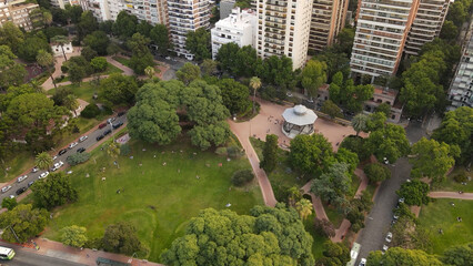 Aerial top down shot of beautiful greened Barrancas de Belgrano Park beside Skyscraper Buildings and traffic on road in Buenos Aires,Argentina
