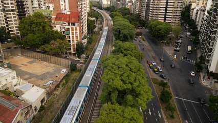 Train driving by railway, through green landscape in Buenos Aires City, Argentina. 4K 60fps. Aerial shot.