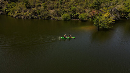 Back view of couple kayaking on river towards shore.