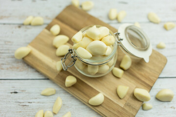 Peeled fresh peeled garlic in a glass jar and scattered on the floor