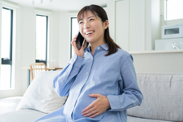 Fototapeta premium 自宅で電話をかける日本人妊婦