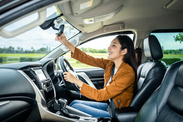 Young beautiful asian women getting new car. she very happy and excited hand adjust the rearview mirror before driving car safety travel.