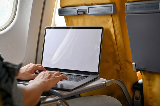 A male passenger in economy class using his portable laptop during the flight. close-up image