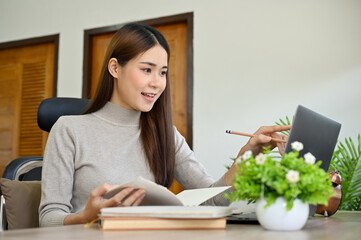 Charming Asian female college student using laptop to search the online information.