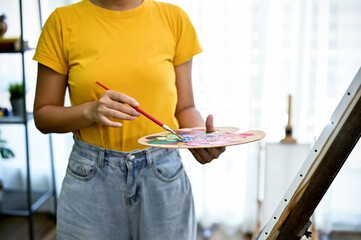 A female painter or artist standing in front of her canvas easel, holding a palette