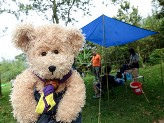 A teddy bear stands in front of a cooking tent, using depth-of-field photography.