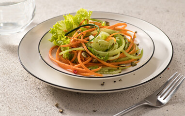 fresh vegetable salad of carrots with cucumber on a white dish and a light background, serving, close-up