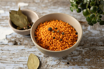 dry yellow lentils; raw legumes in a bowl; cooking ingredient; wooden background; horizontal format