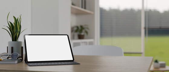 Digital tablet mockup with wireless keyboard is on a table over blurred living room background.