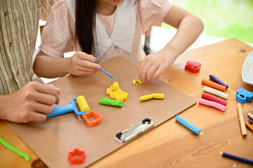 Above view, A cute little young Asian girl sculpting and moulding play dough with her dad