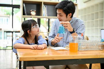 A cute young Asian girl studying science at home with her private tutor.