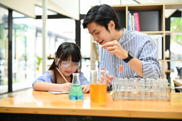 A handsome Asian male science teacher explaining the science experiment result to his student.