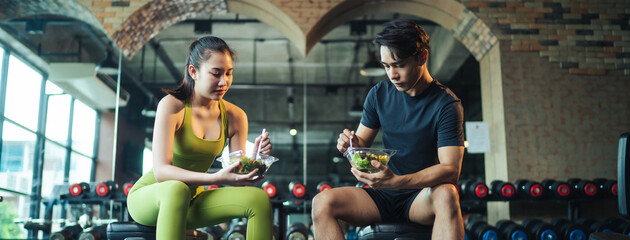 Healthy lifestyle. Asian couple healthy eating salad after exercise at fitness gym. Asian man and...