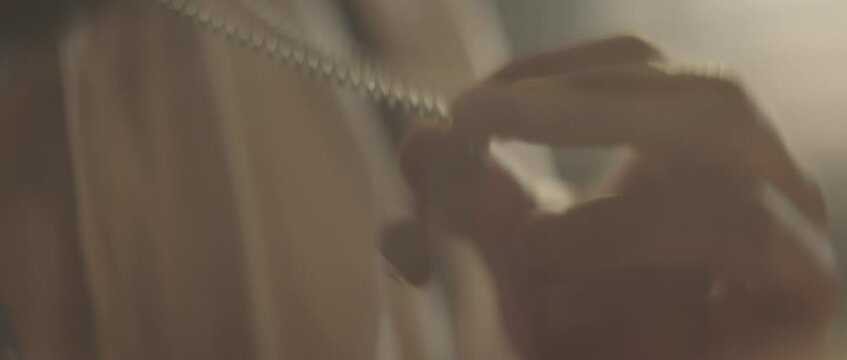 Close-up footage of putting valuable key into holder and hiding under shirt. Retro style detective using deduction for solving challenging cases.