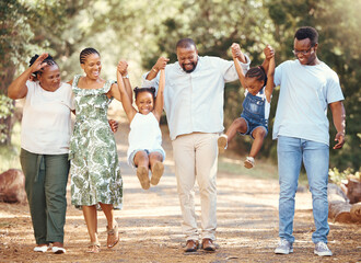 Happy black family bonding and having fun at a park together, laughing and playful holding hands on...