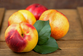 fresh nectarines with leaves on wooden background.