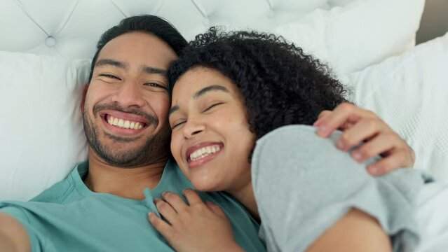 Interracial couple taking selfie with phone in bed, streaming video for social media while relax in bedroom and smile for happy marriage in house. Comic, love and happiness man and woman with photos