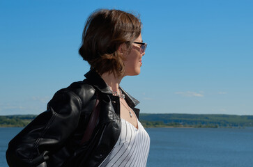 Portrait of woman in leather clothes on summer riverbank