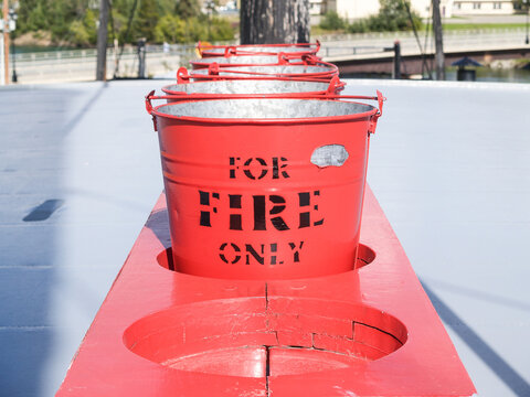 Row of red buckets in rack with sign for fire only