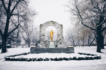 Johann Strauss statue in the public Vienna City Park. Snow covered city during winter.