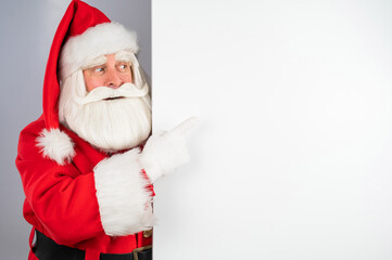 Santa Claus peeks out from behind an ad on a white background. Merry Christmas.