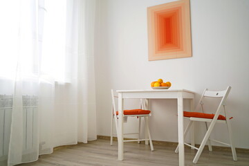 A white square table with chairs and fruit in the kitchen.