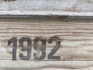 On a weathered wooden board is printed in black paint the number 1992