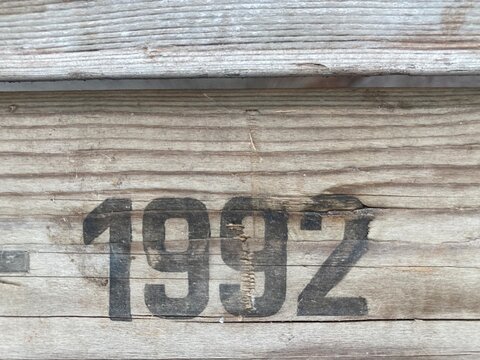 On a weathered wooden board is printed in black paint the number 1992