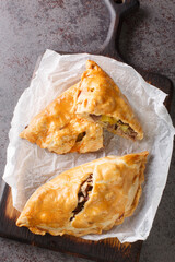 Traditional Cornish pasty filled with beef meat, potato and vegetables closeup on the paper on the...