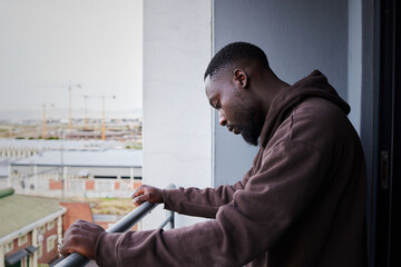 Depression, sad and mental health with a man feeling anxiety, angry or frustrated out on a balcony alone. Fail, depressed and problem with a young male in grief or fear and having a difficult problem