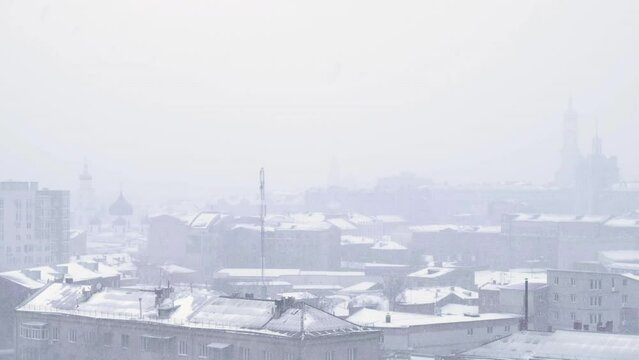 Winter weather. Urban snow storm. City view blurred from falling snow