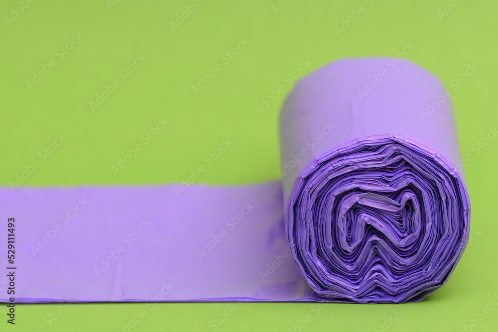 Wall mural Tightly packed non-recyclable purple rubbish garbage trash bag flat roll unfolded going out of frame lime green background  - Wall murals