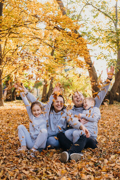 Portrait of a happy beautiful family posing while having fun in autumn forest playing and throwing leaves. Love, relationship, family, season and people concept